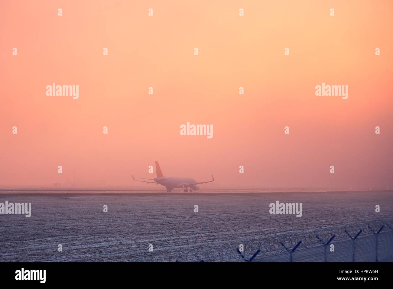 Einfrieren von Nebel am Flughafen. Flugzeug beim goldenen Sonnenuntergang ausziehen. Stockfoto