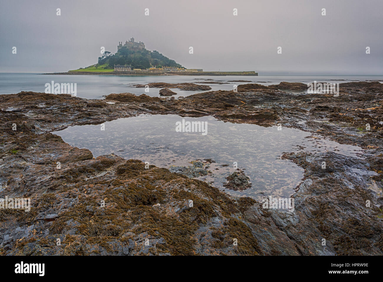 Dawn erschossen am nebligen Morgen mit langer Belichtungszeit von St Michaels Mount mit Rock Pool im Vordergrund, West Cornwall, England, UK im Februar Stockfoto