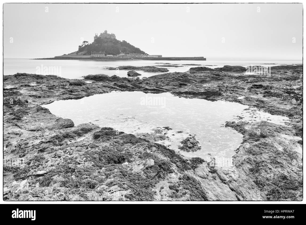 Schwarz & weiß Morgendämmerung erschossen am nebligen Morgen mit langer Belichtungszeit von St Michaels Mount mit Rock Pool im Vordergrund, West Cornwall, England, UK im Februar Stockfoto