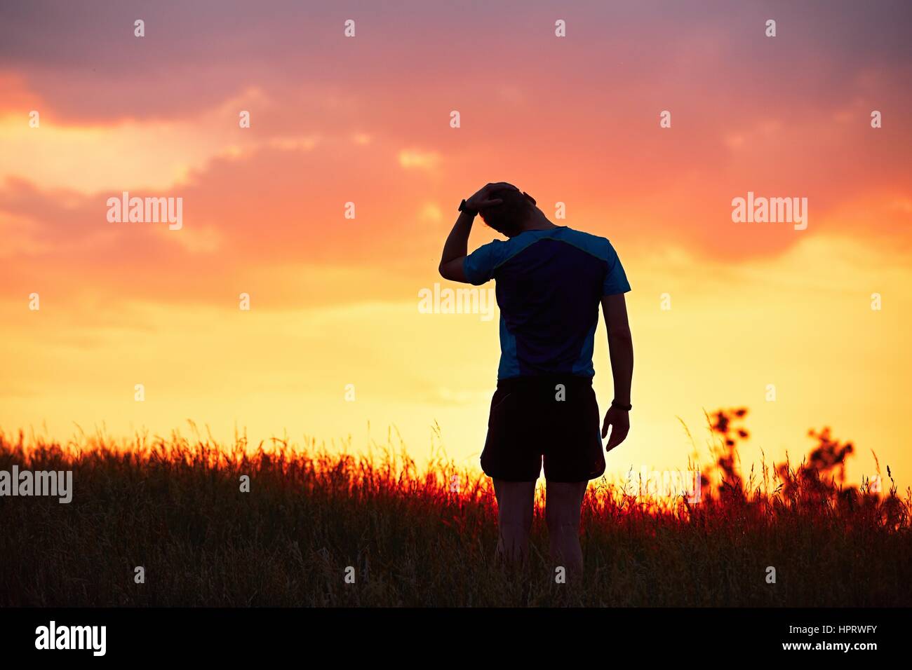 Silhouette des Läufers. Outdoor-cross-country Rennen. Männliche Läufer tun Dehnübungen und Vorbereitung für Training während der goldenen Sonnenuntergang. Stockfoto