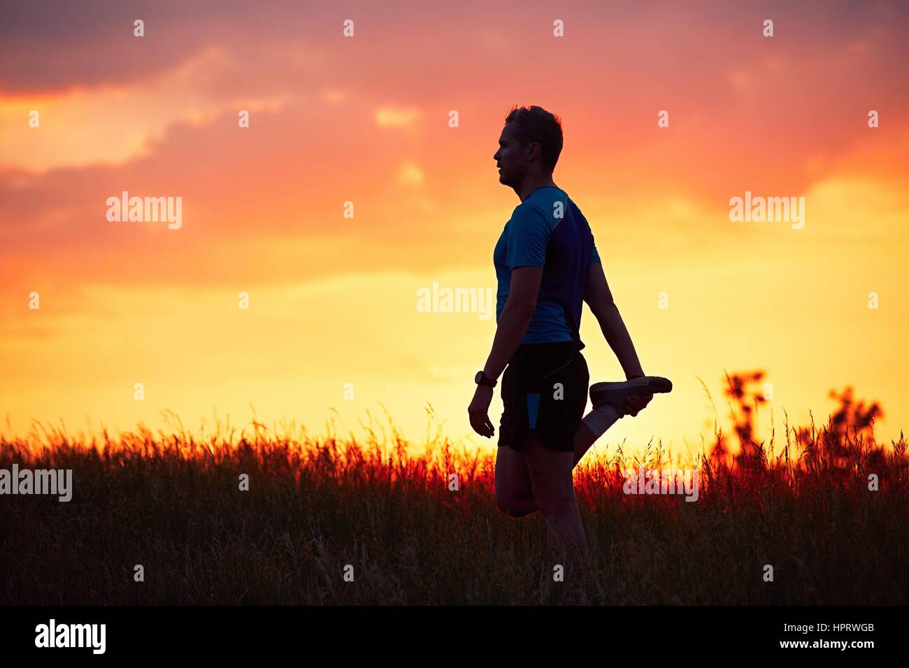 Silhouette des Läufers. Outdoor-cross-country Rennen. Männliche Läufer tun Dehnübungen und Vorbereitung für Training während der goldenen Sonnenuntergang. Stockfoto