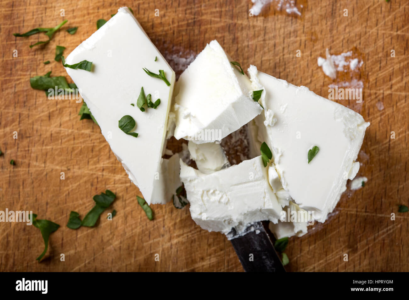 Feta Käse Stücke mit Messer und Kräutern auf hölzernen Hintergrund Stockfoto