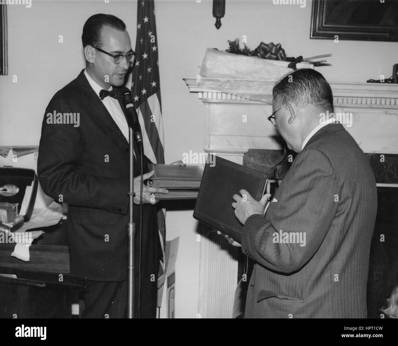 Fünfte Archivar der Vereinigten Staaten Dr. James B. Rhoads präsentiert ein Buch von Hommagen an Dritte Archivar der Vereinigten Staaten Dr. Wayne C. Grover bei seiner Abschiedsfeier im Empfangsraum des Archivars des Gebäudes National Archives in Washington, DC, 5. November 1965. Stockfoto
