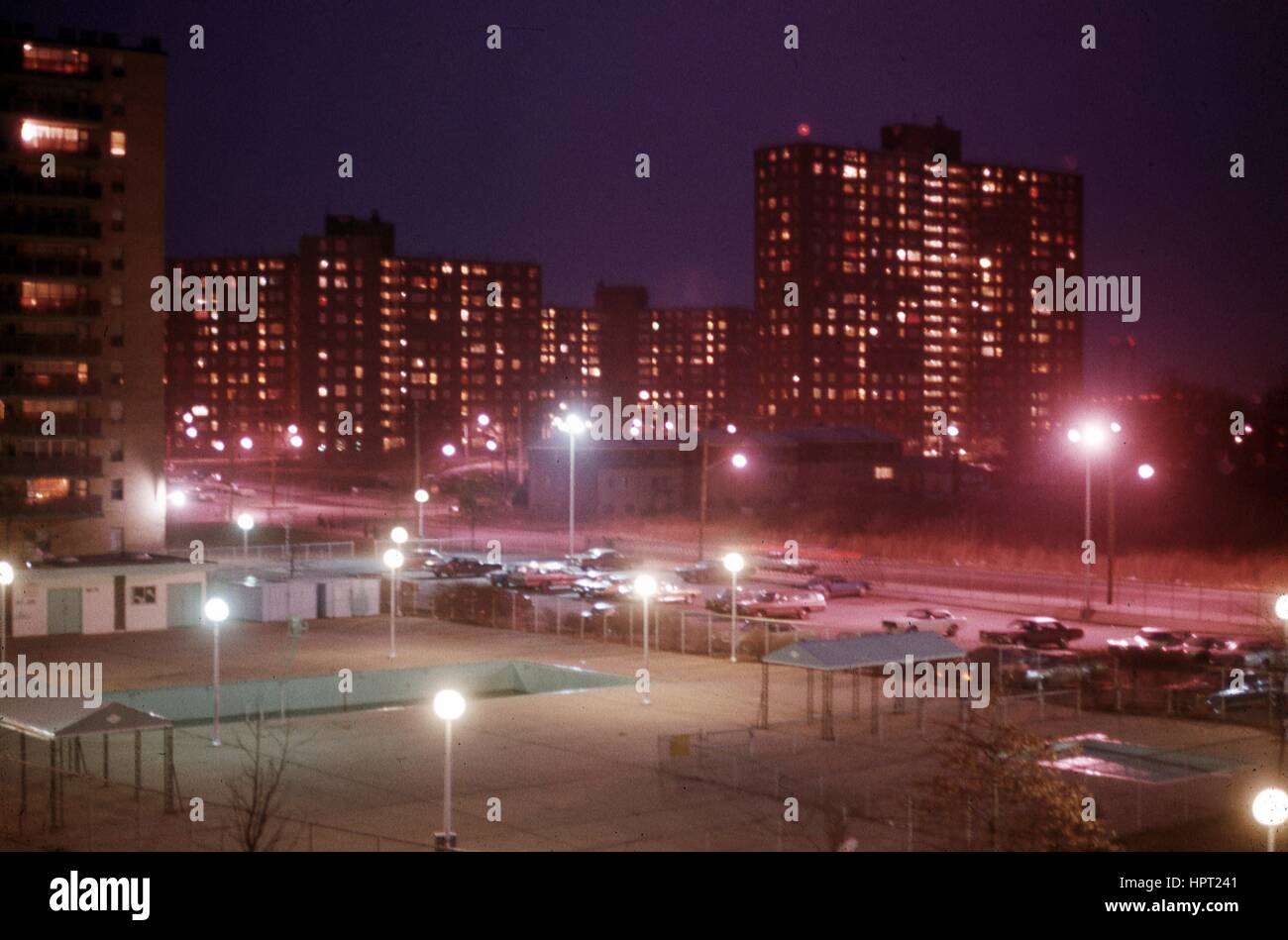 Straßenlaternen beleuchten einen Parkplatz und Sportplätze in einem Park in der Nähe von ein Wohnprojekt in der Bronx, New York City, New York, 1974. Stockfoto