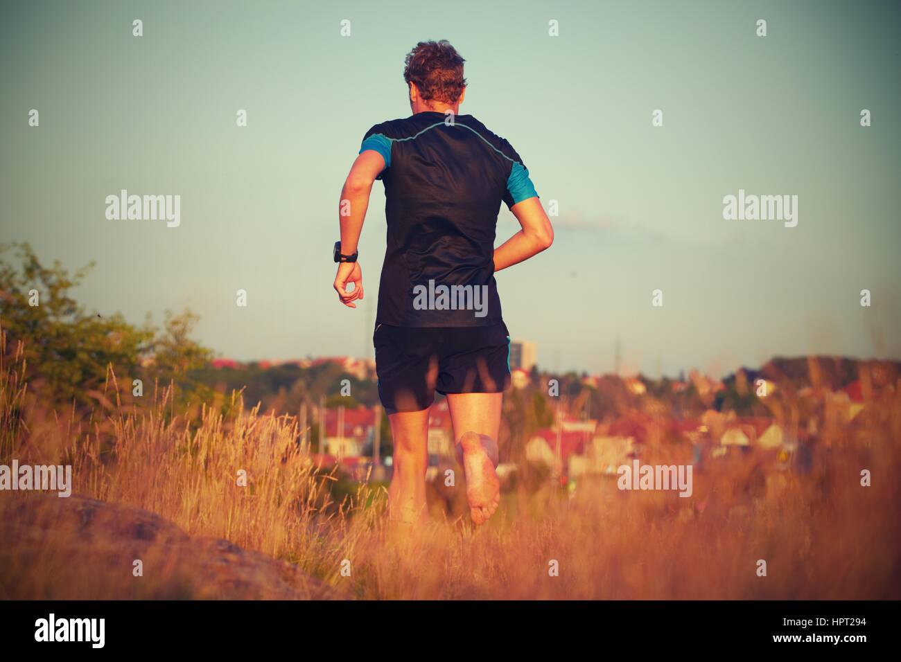 Junger Mann läuft auf Sommerwiese - schönes Abendlicht Stockfoto