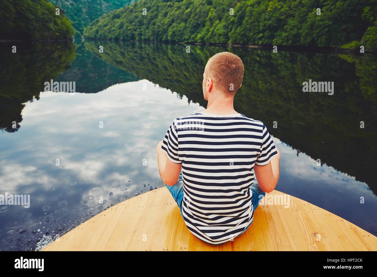 Urlaubsreise auf dem Fluss. Gut aussehender Mann sitzt auf dem Bug des Bootes. Stockfoto