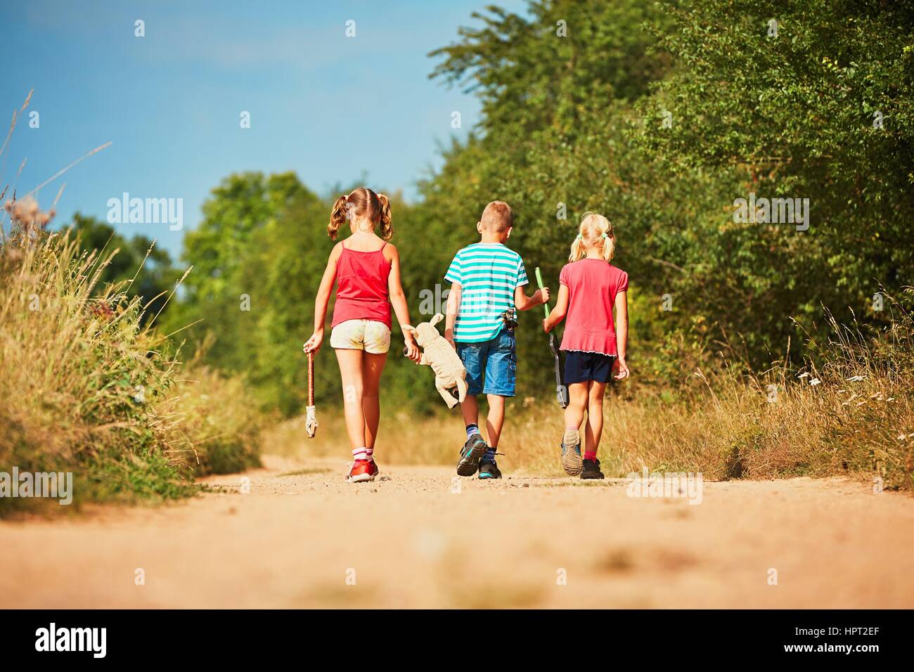 Geschwister in der Natur. Zwei Mädchen und ein Junge Spielzeug halten und gehen zu spielen. Stockfoto