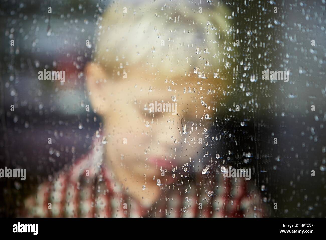 Kleiner Junge hinter dem Fenster im Regen - selektiven Fokus Stockfoto