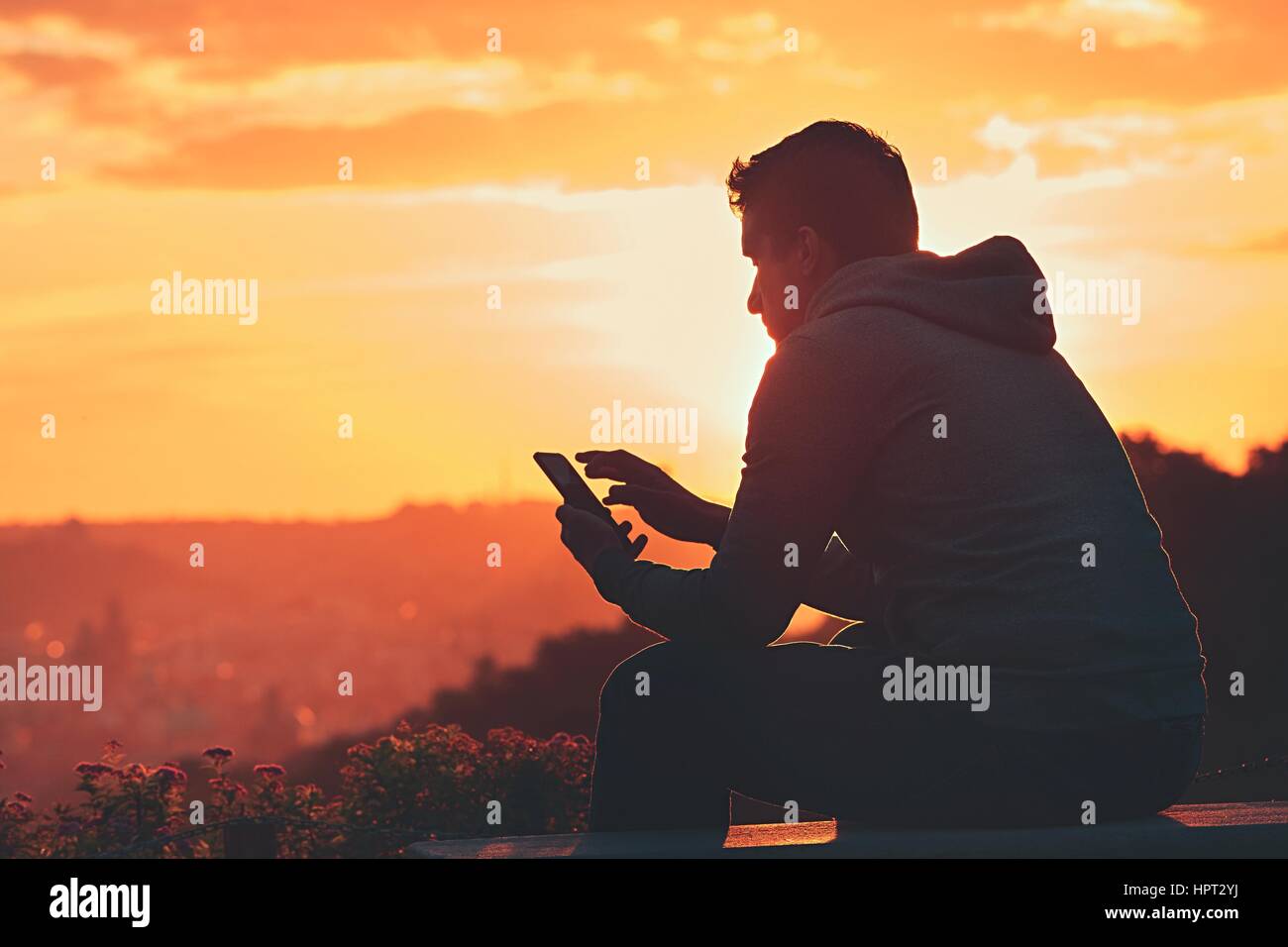 Junger Mann mit Handy auf den Sonnenaufgang. Stockfoto