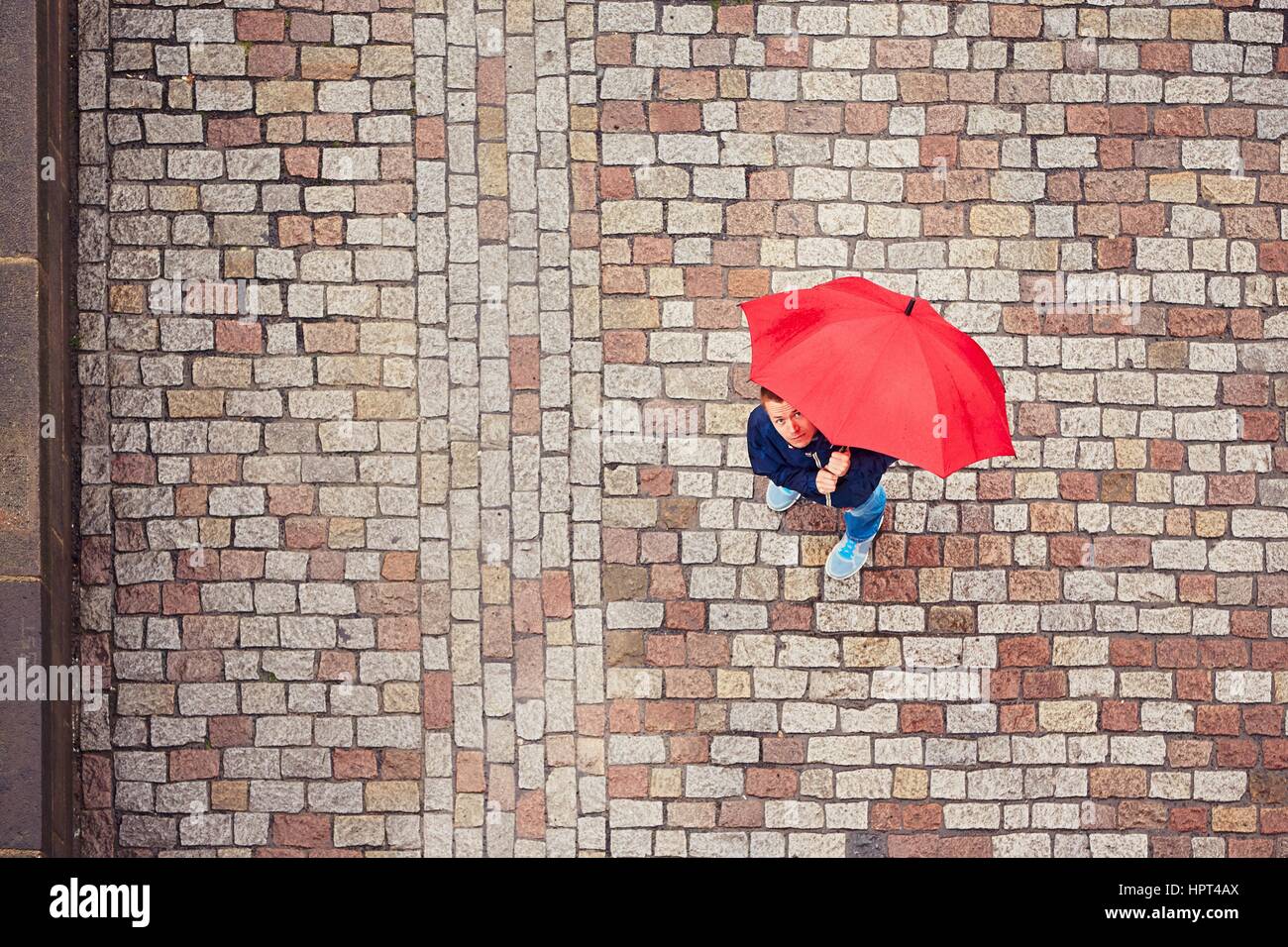Regnerischen Tag. Junger Mann hält roten Regenschirm und Wandern in Regen. Straße von Prag, Tschechische Republik. Stockfoto
