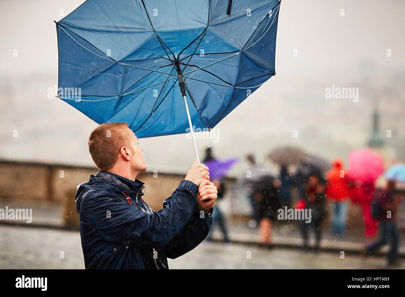Regen Sie in der Stadt. Junger Mann hält blaue Regenschirm bei Gewitter. Straße von Prag, Tschechische Republik. Stockfoto