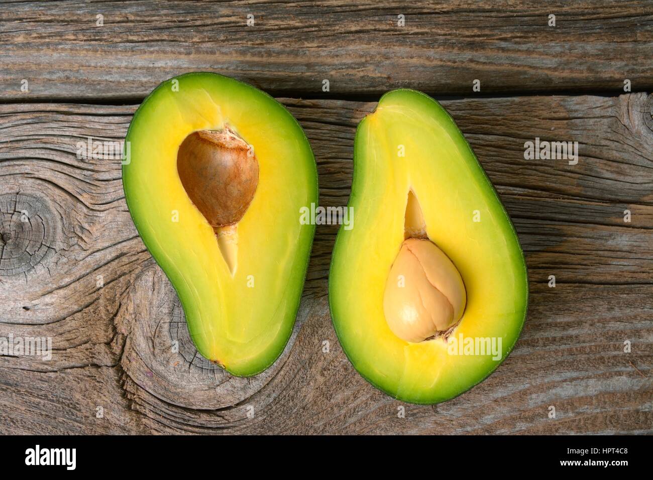 Avocados Schneiden einer in zwei mit Samen auf Holzuntergrund Stockfoto