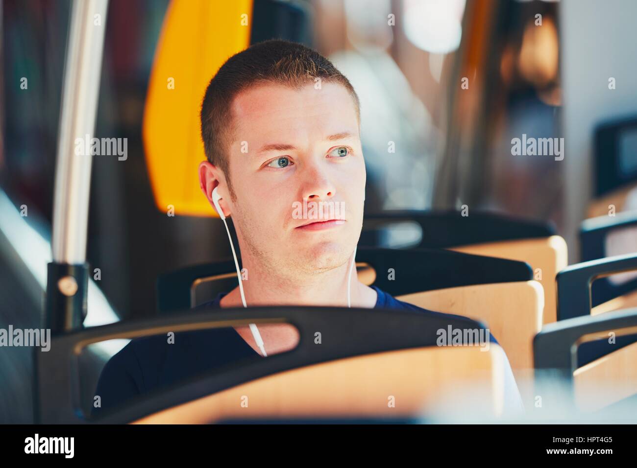 Alltag und pendeln zur Arbeit mit öffentlichen Verkehrsmitteln. Hübscher junger Mann ist mit der Straßenbahn unterwegs. Mann trägt Kopfhörer und Musi hören Stockfoto