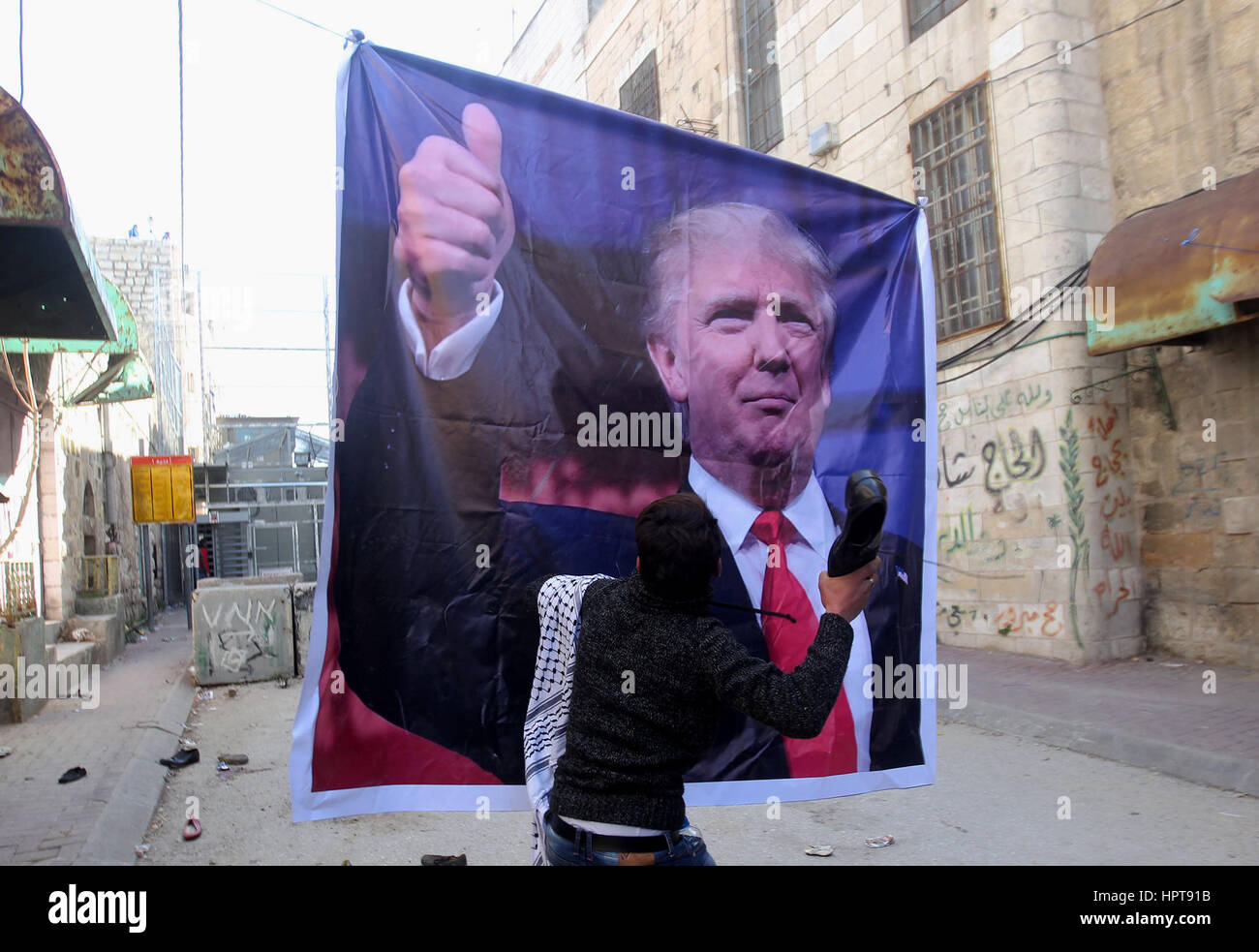 Hebron, Westjordanland, Palästinensische Gebiete. 24. Februar 2017. Ein palästinensischer Demonstrator wirft ein Alter Schuh auf einem Plakat von US-Präsident Donald Trump wie sie protestieren gegen seine Unterstützung für Israel und die Nachfrage für die israelische Armee Shuhada Straße, wieder zu öffnen, die weitgehend für Palästinenser gesperrt ist, in der West Bank von Hebron auf Kredit-24. Februar 2017: Wisam Hashlamoun/APA Bilder/ZUMA Draht/Alamy Live News Stockfoto