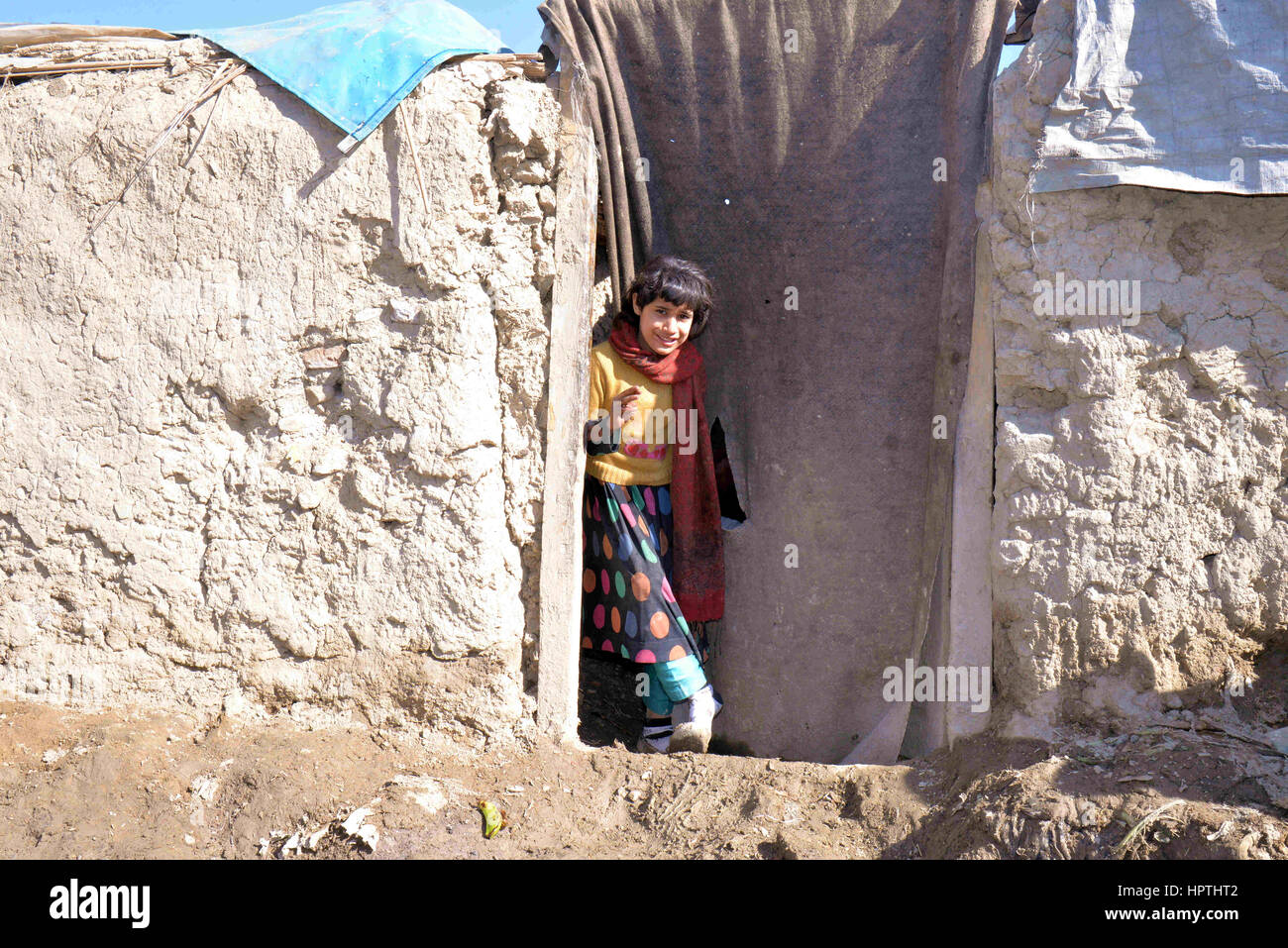 Kabul, Afghanistan. 23. Februar 2017. Eine Mädchen steht vor ihrem Haus im nördlichen Stadtteil von Kabul, Afghanistan, am 23. Februar 2017. Winter hat fast bedeckt, Afghanistan, Auswirkungen auf das Leben der armen Familien, vor allem diejenigen, die keine Erwärmung Ausrüstung, sauberes Wasser oder genug zu essen, mit dem kalten Wetter zu bewältigen haben. In den nördlichen Stadtteil von Kabul viele Leben noch immer in Schlamm Gebäuden und haben kein Geld zum Kauf von Holz, Feuer. Bildnachweis: Dai He/Xinhua/Alamy Live-Nachrichten Stockfoto