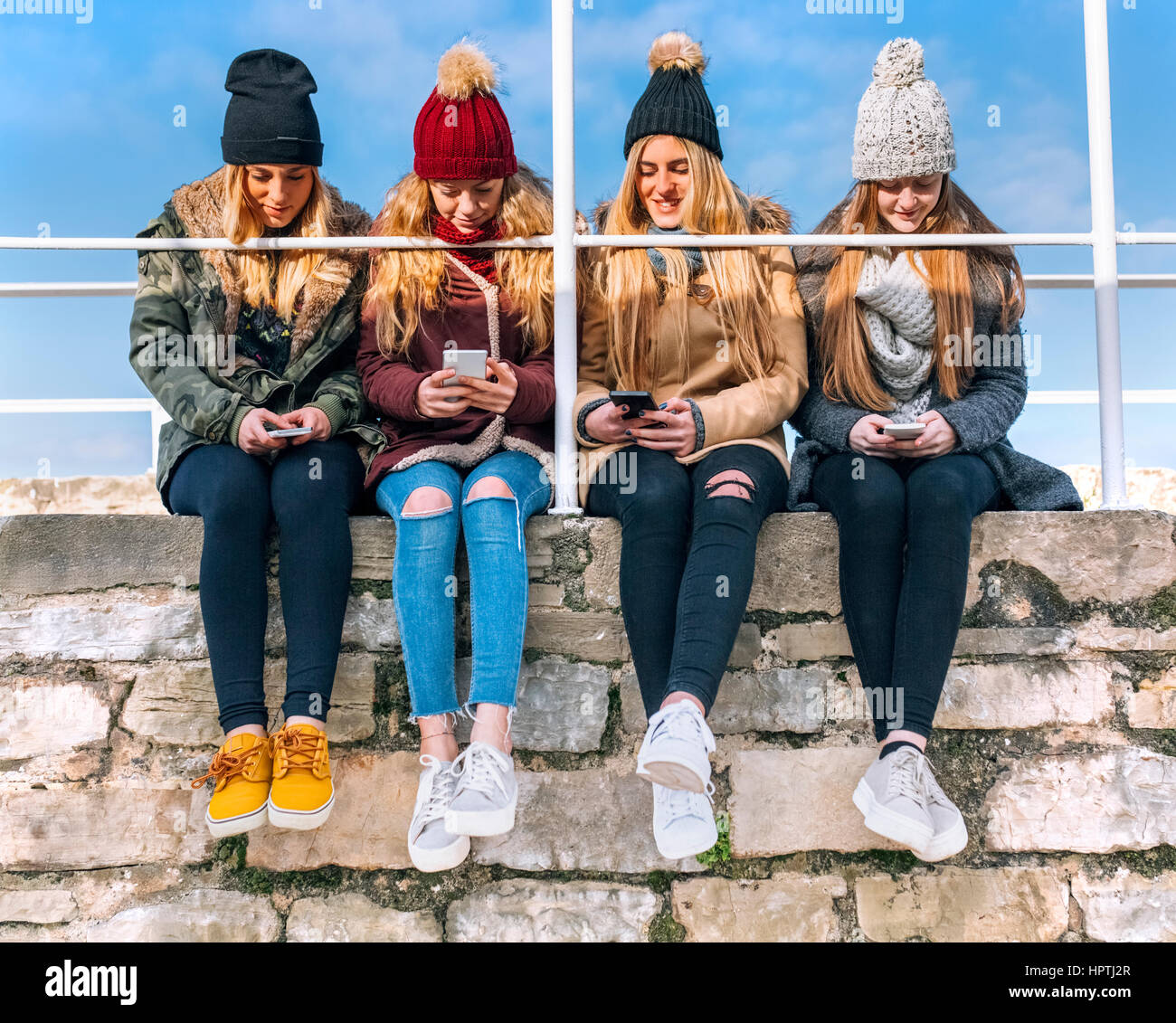 Vier Freunde sitzen nebeneinander an eine Wand Text messaging Stockfoto