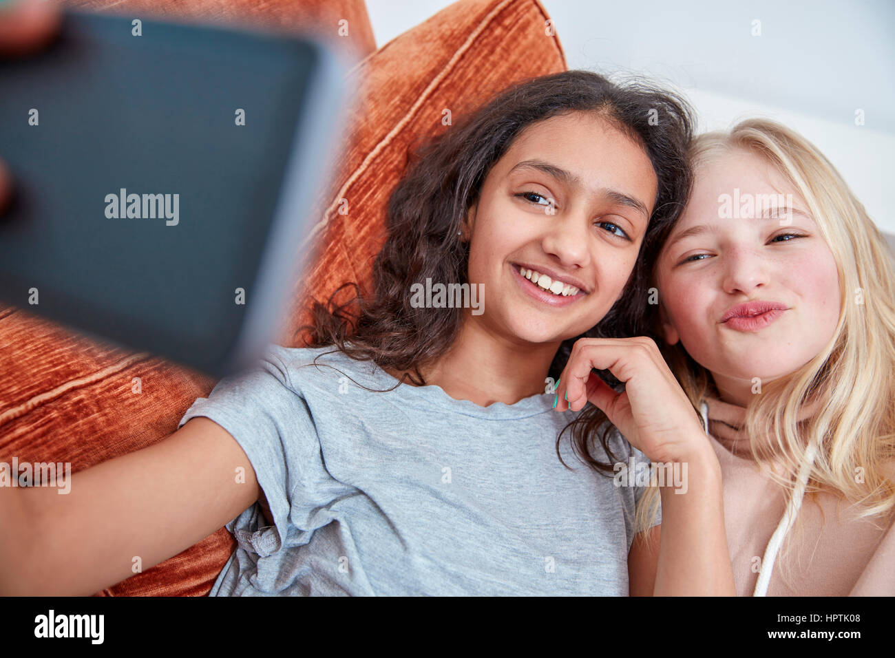 Zwei glückliche Mädchen auf Couch nehmen ein Selbstporträt Stockfoto
