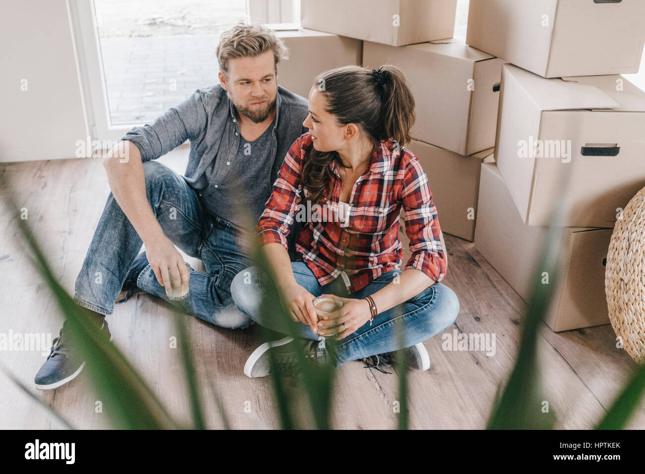 Paar sitzt am Boden neben Umzugskartons Stockfoto