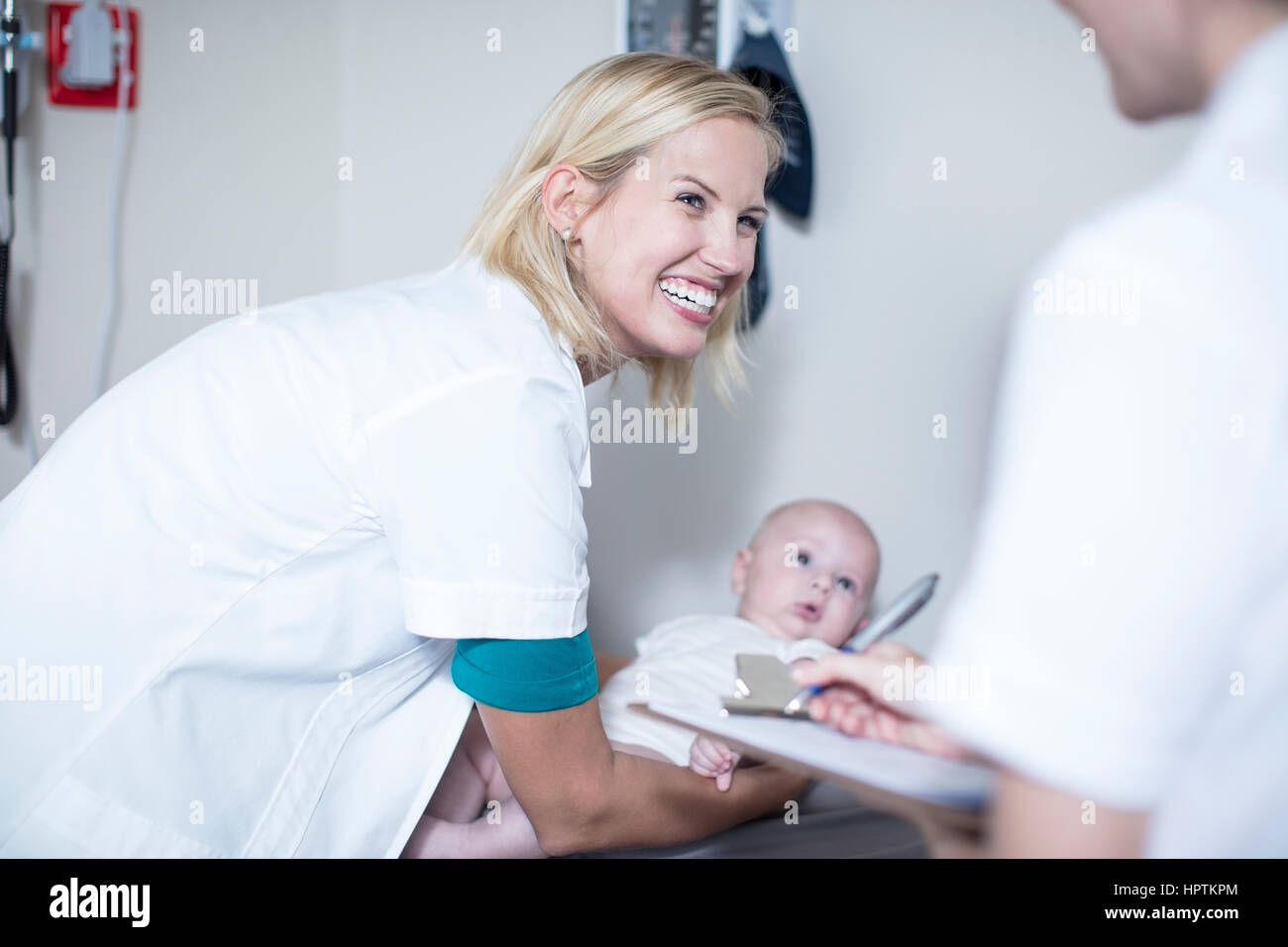 Weibliche Pedeatrician Holding Baby bei Untersuchung Stockfoto