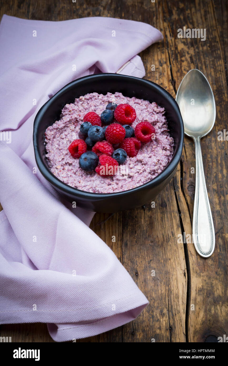 Schüssel mit Übernachtung Haferflocken mit Heidelbeeren und Himbeeren auf Holz Stockfoto