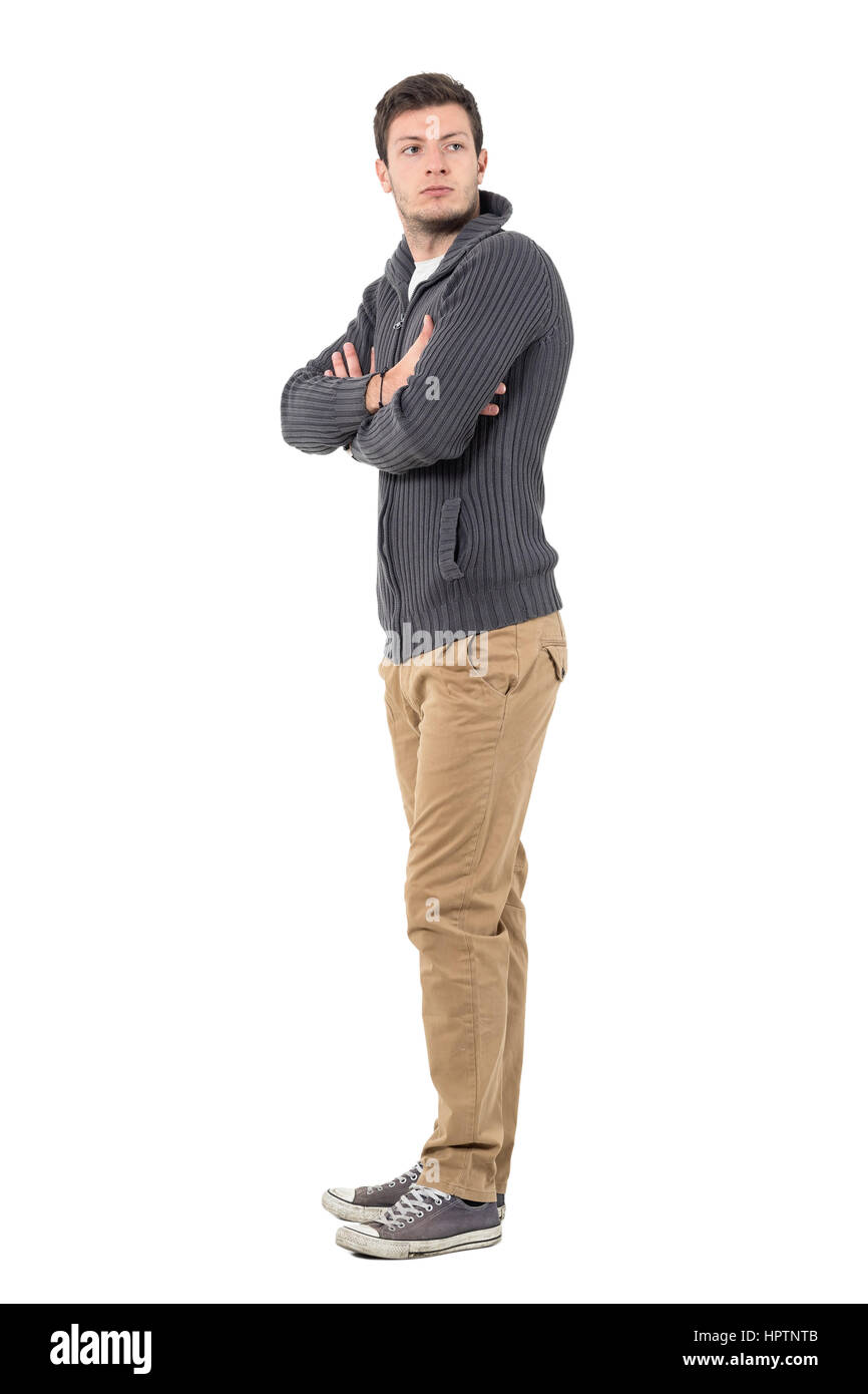 Seitenansicht des jungen legerer Mann mit verschränkten Armen rückblickend über die Schulter. Ganzkörper-Länge-Porträt isoliert auf weißem Hintergrund Stockfoto