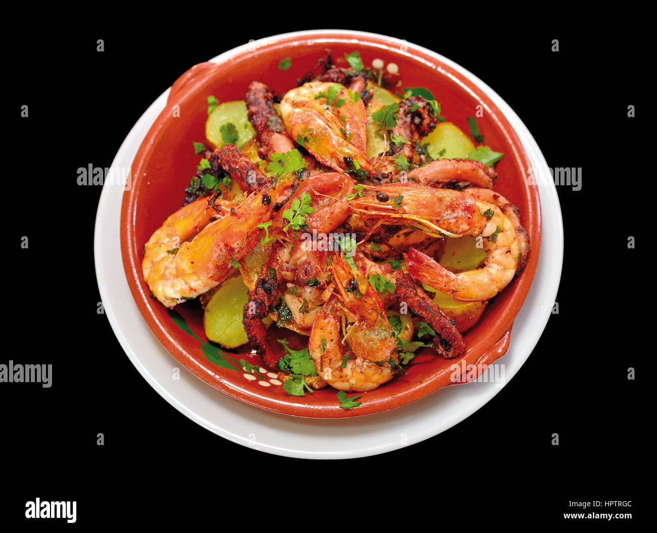 Nahaufnahme von einem Oktopus und Garnelen Gericht in einer Teracotta-Platte mit schwarzem Hintergrund Stockfoto