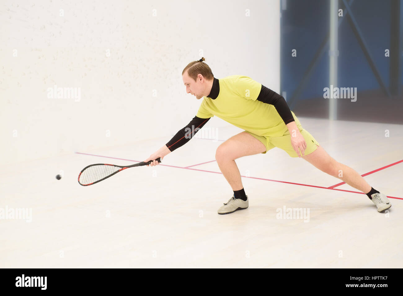 junge kaukasischen Squashspieler Kollision mit einem Ball in einen Squash-Court. Squashspieler in Aktion. Mann Spiel Match Squash. Squash-Sportaktivitäten Stockfoto