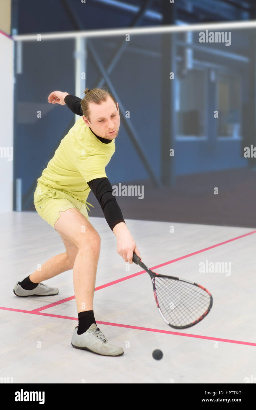 junge kaukasischen Squashspieler Kollision mit einem Ball in einen Squash-Court. Squashspieler in Aktion. Mann Spiel Match Squash. Squash-Sportaktivitäten Stockfoto