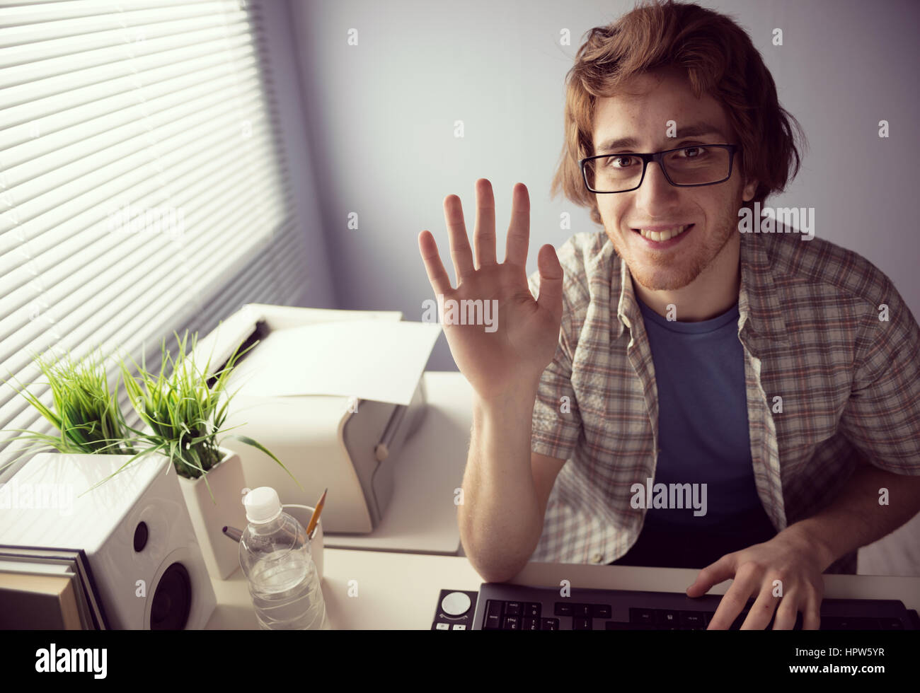 Junge freundliche Kerl auf Webcam Lächeln und winken Hand. Stockfoto