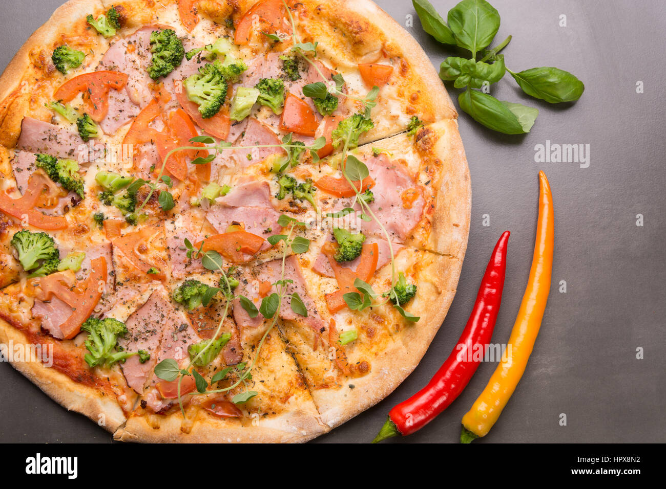 Draufsicht der Pizza mit Schinken, Tomaten und Brokkoli mit frischem Oregano Kräuter Stockfoto