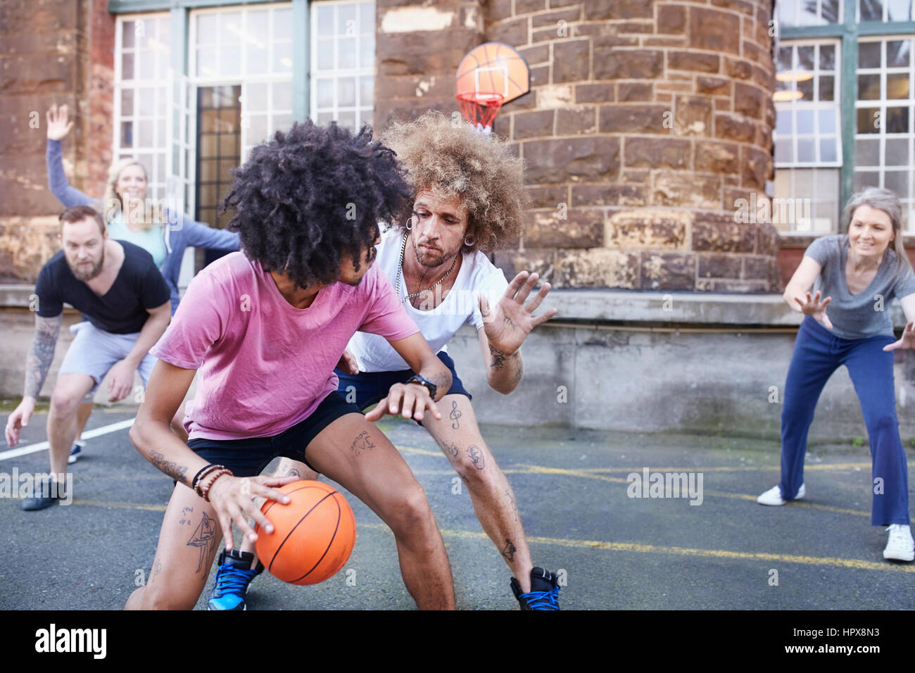 Freunde spielen Basketball auf städtischen Basketballplatz Stockfoto