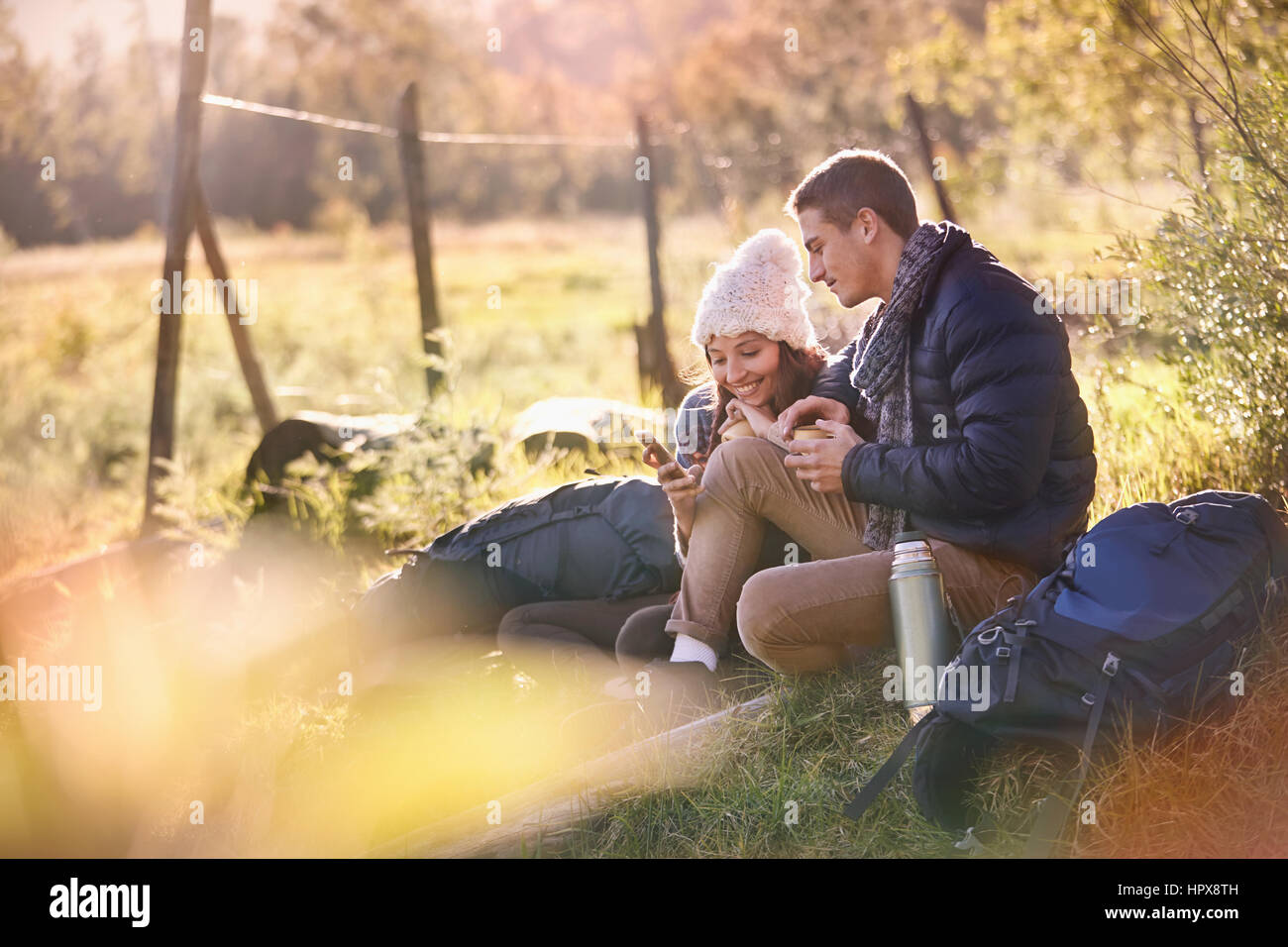 Junges Paar Wanderer ruht in sonnigen Rasen mit Handy und digitale Tablett Stockfoto
