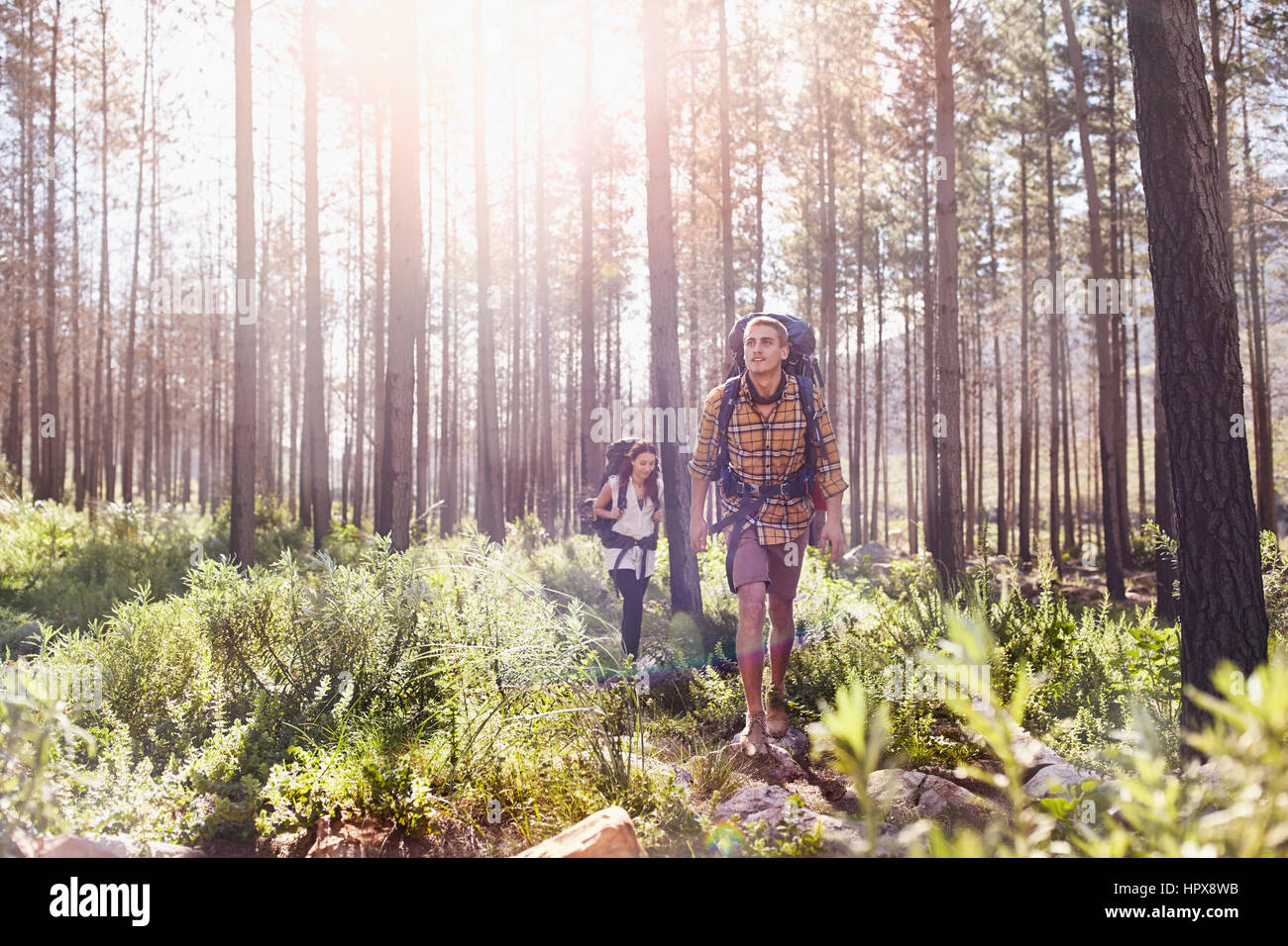 Junges Paar mit Rucksack wandern im sonnigen Wald Stockfoto