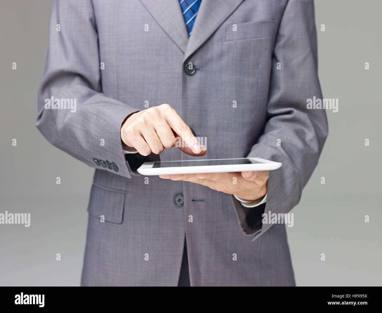 Geschäftsmann im Anzug mit einem Tablet-Computer, grauen Hintergrund. Stockfoto