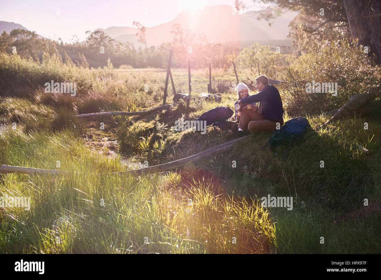 Junges Paar mit Rucksack wandern, Ausruhen im sonnigen entlegenen Feld Stockfoto