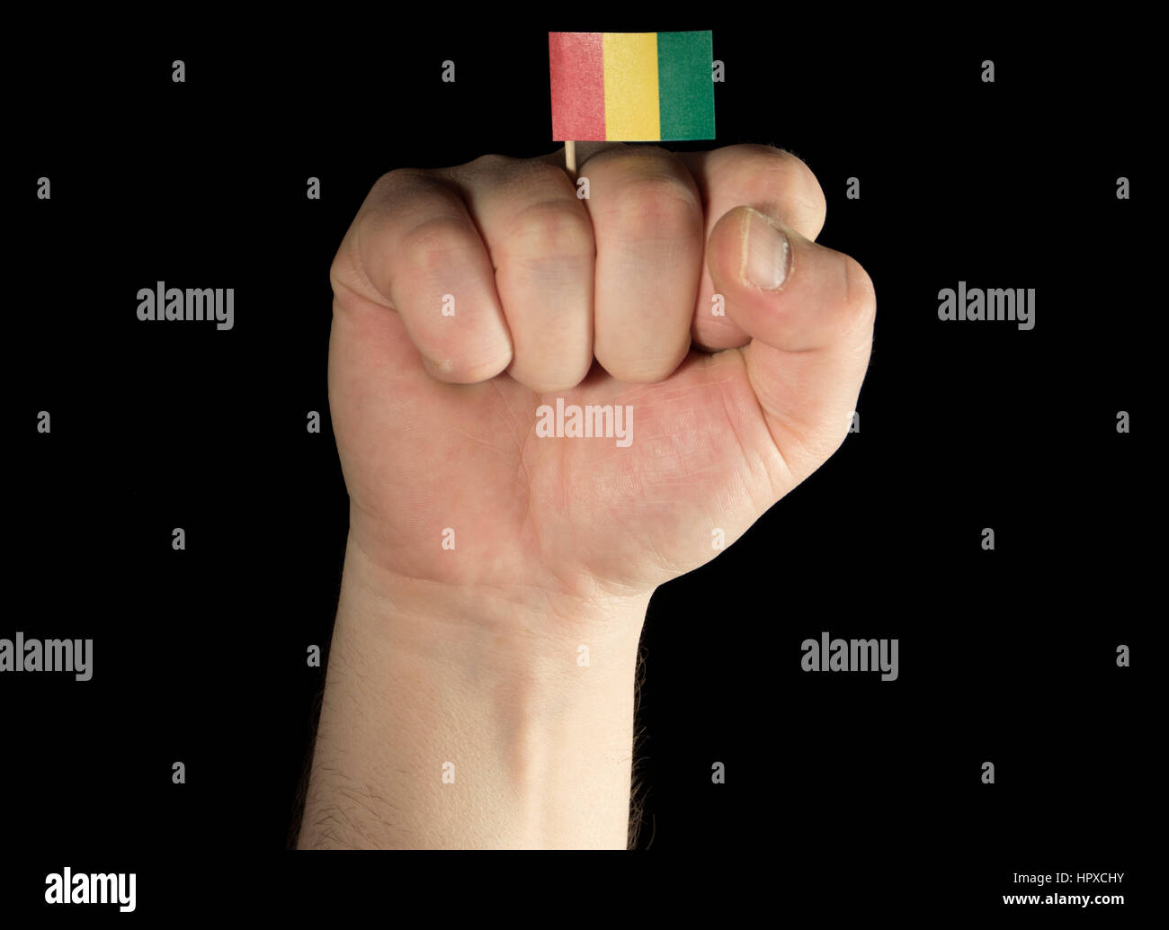 Mann Hand Faust mit Guineas Flagge auf schwarzem Hintergrund isoliert Stockfoto