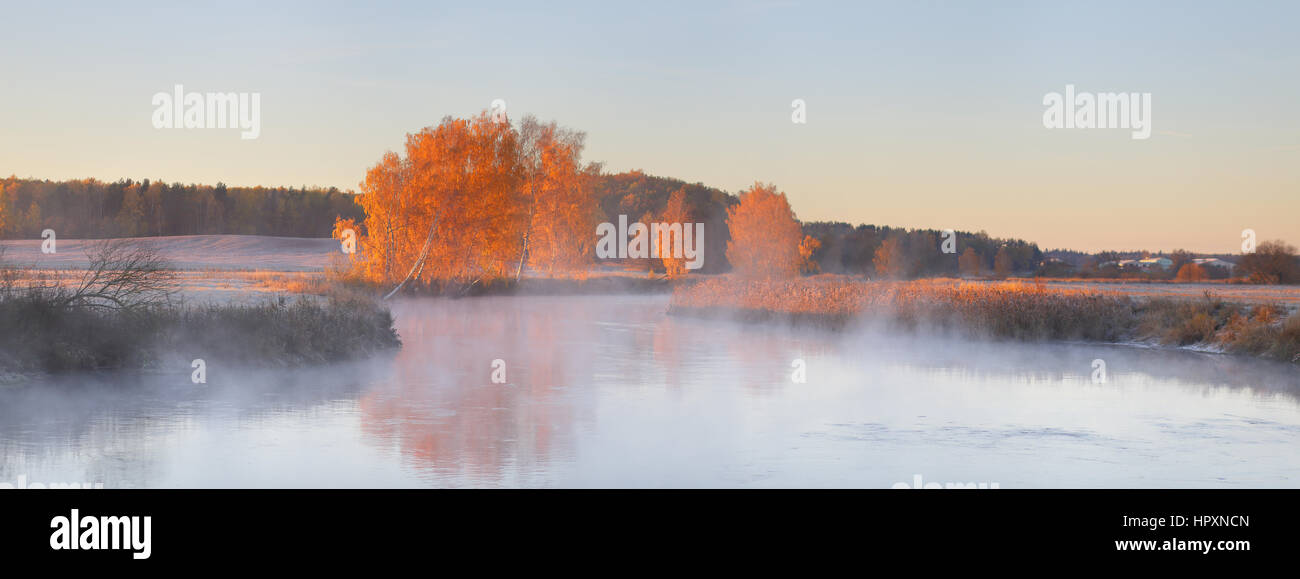 Panorama-Landschaft Herbst Sonnenaufgang. Bäume spiegeln sich im See. Misty Herbstmorgen. Stockfoto