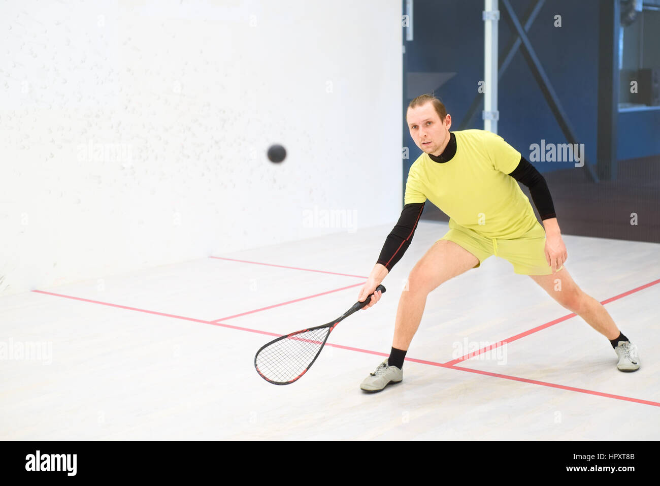 junge kaukasischen Squashspieler Kollision mit einem Ball in einen Squash-Court. Squashspieler in Aktion. Mann Spiel Match Squash Stockfoto