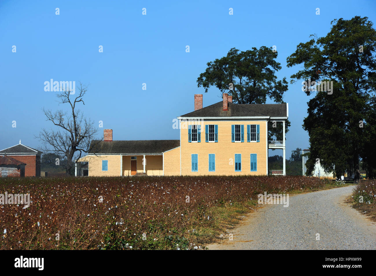 Straße führt zum Lakeport Plantage im Mississippi-Delta-Bereich von Arkansas.  Zweistöckigen Haus ist aus Holz und lackiert gelb mit blauen Fensterläden. Stockfoto