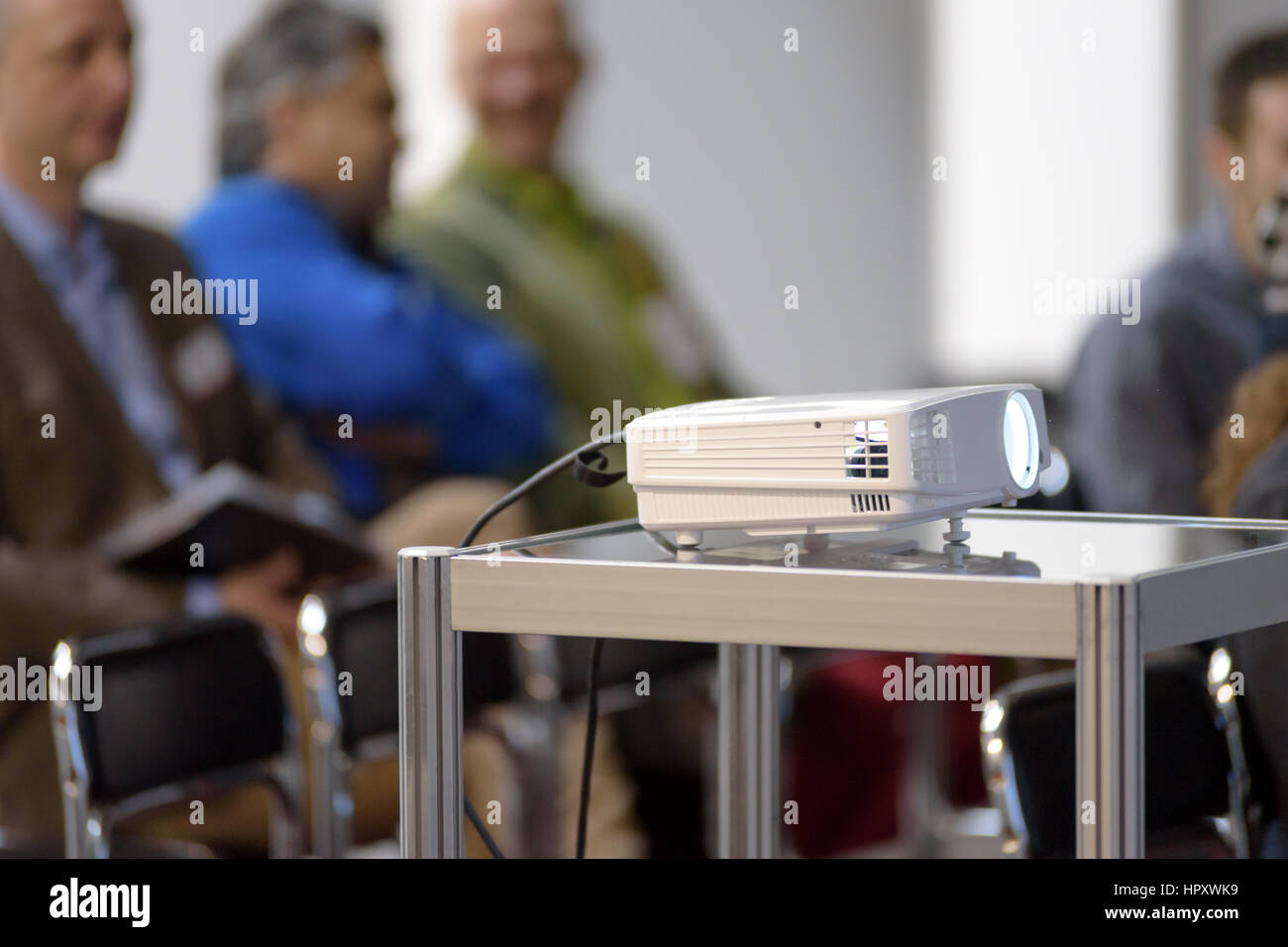 Weiße Multimedia-Projektor in einem Konferenzraum mit Bewegungsunschärfe Menschen auf dem Hintergrund Stockfoto