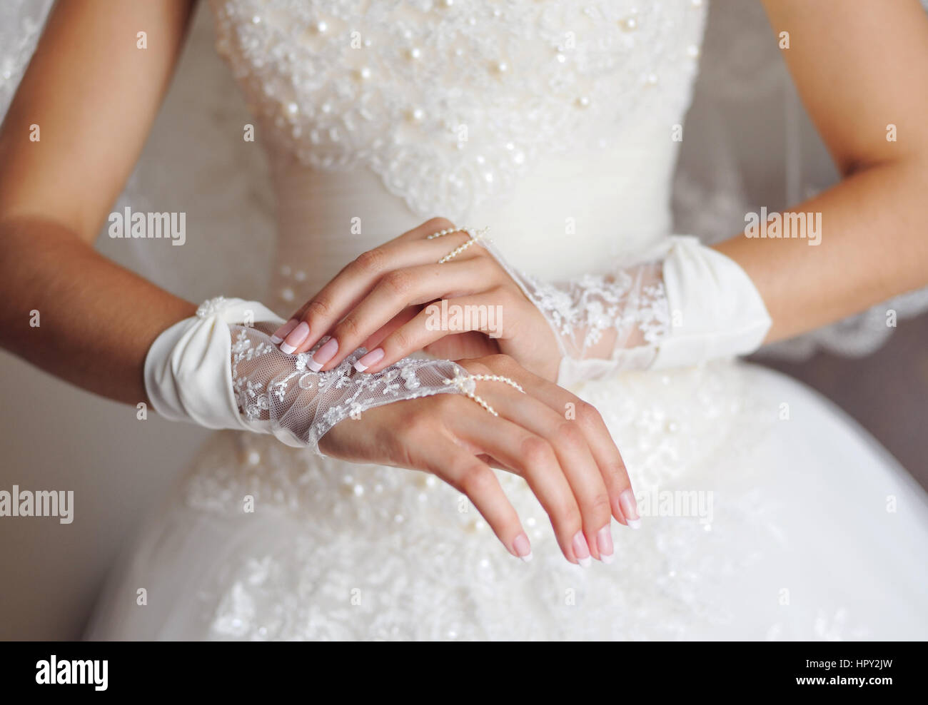 Braut im weißen Kleid bringt Handschuhe auf Händen. Stockfoto