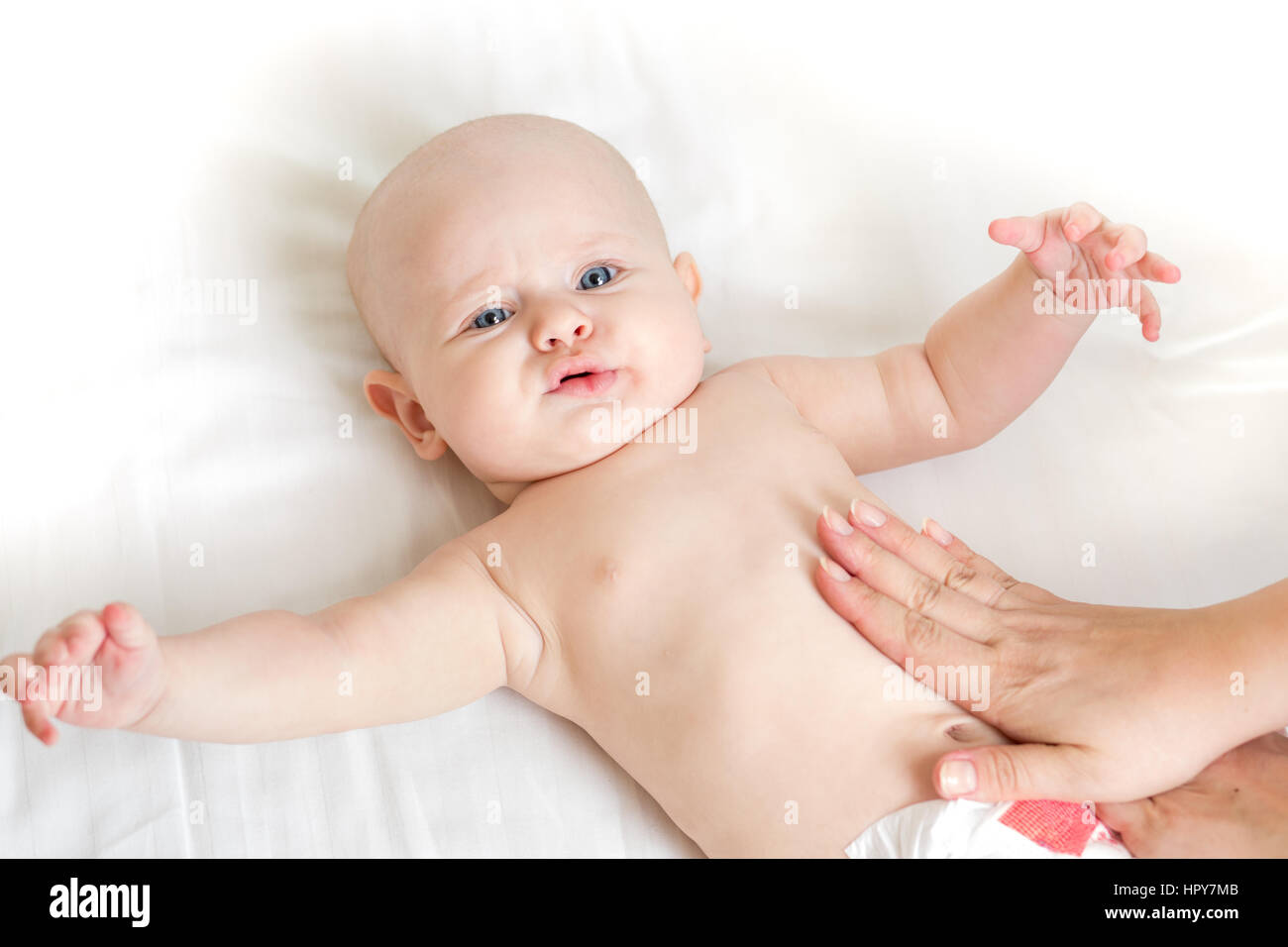Baby-Massage auf dem Rücken zu Hause auf dem Bett liegend Stockfoto