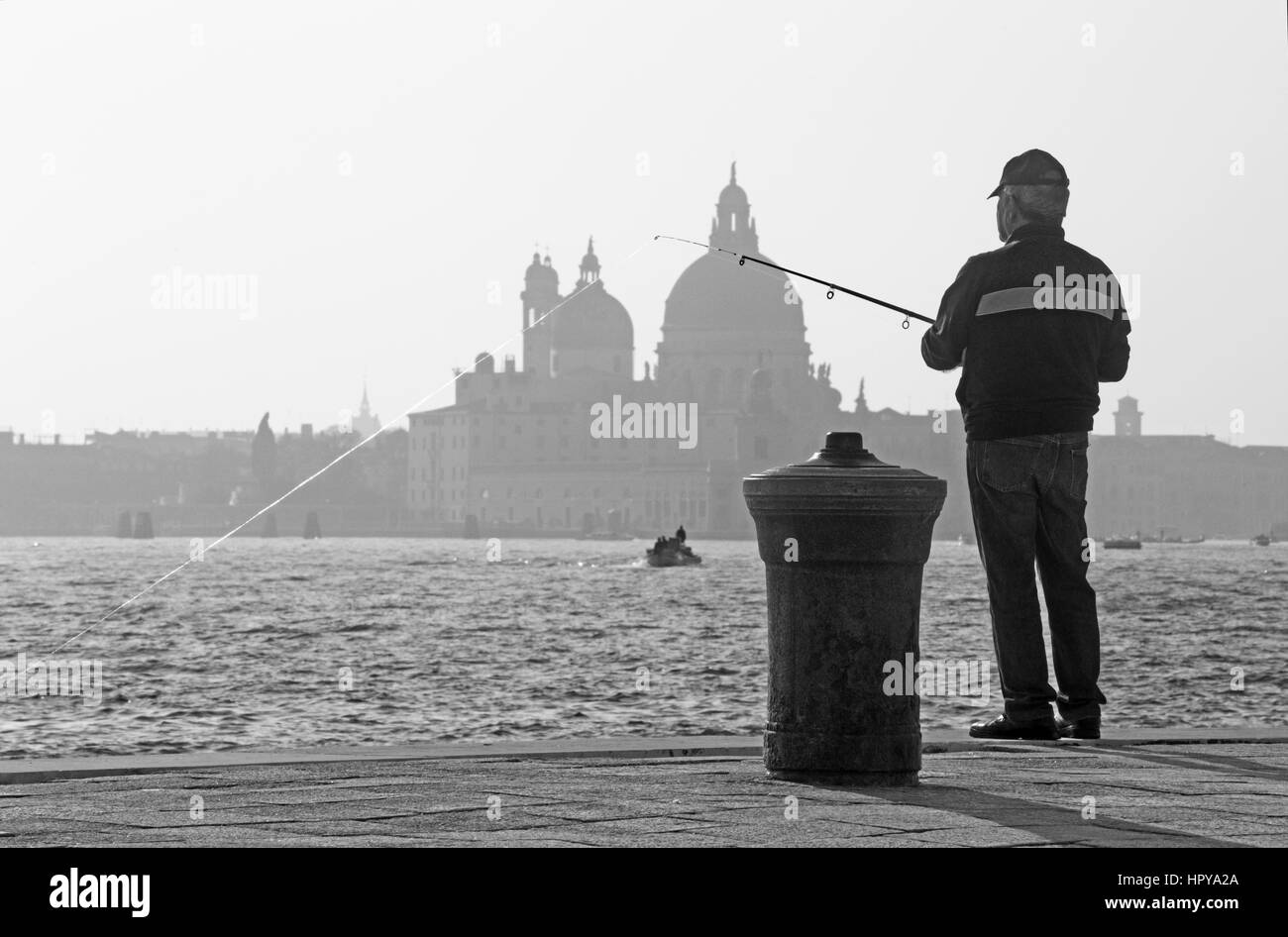 Venedig, Italien - 14. März 2014: Fischer aus Riva S. Biagio Waterfront und Silhouette der Kirche Santa Maria della Salute. Stockfoto