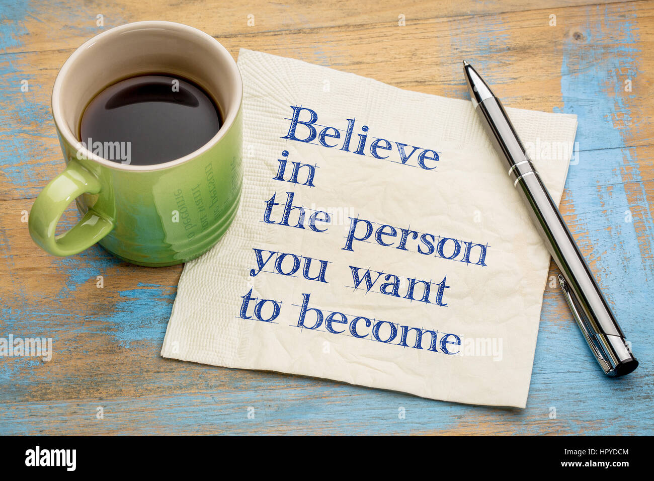 Glauben Sie an die Person, die Sie zu werden-Handschrift auf einer Serviette mit einer Tasse Espressokaffee Stockfoto
