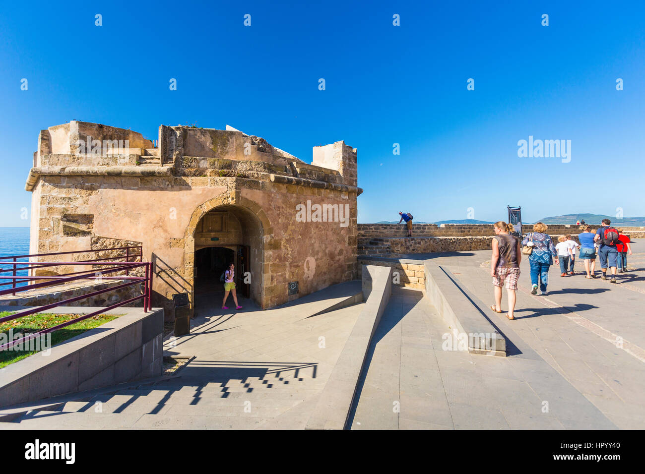 Ein Tourist Wolking entlang der Stadtmauer von Alghero, Sassari, Sardinien, Italien Stockfoto