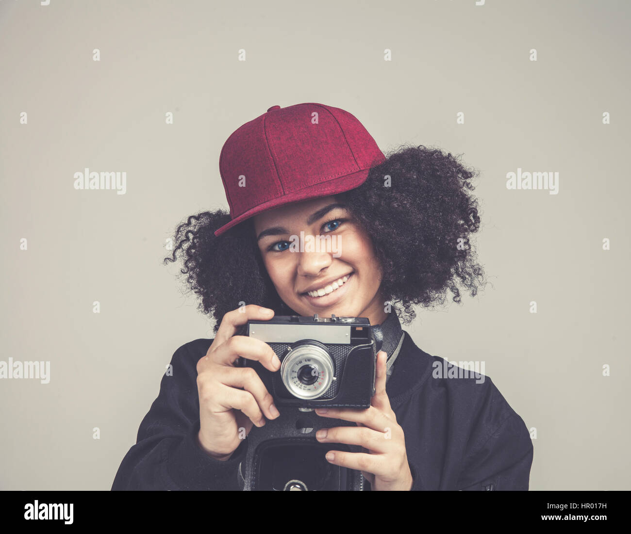 Porträt von ziemlich afrikanischen drausen junge Teenager Hipster Woman Modell mit Retro-Foto-Kamera trägt einen rosa Hut, schwarze Lederjacke. Fashion-Look. Stockfoto