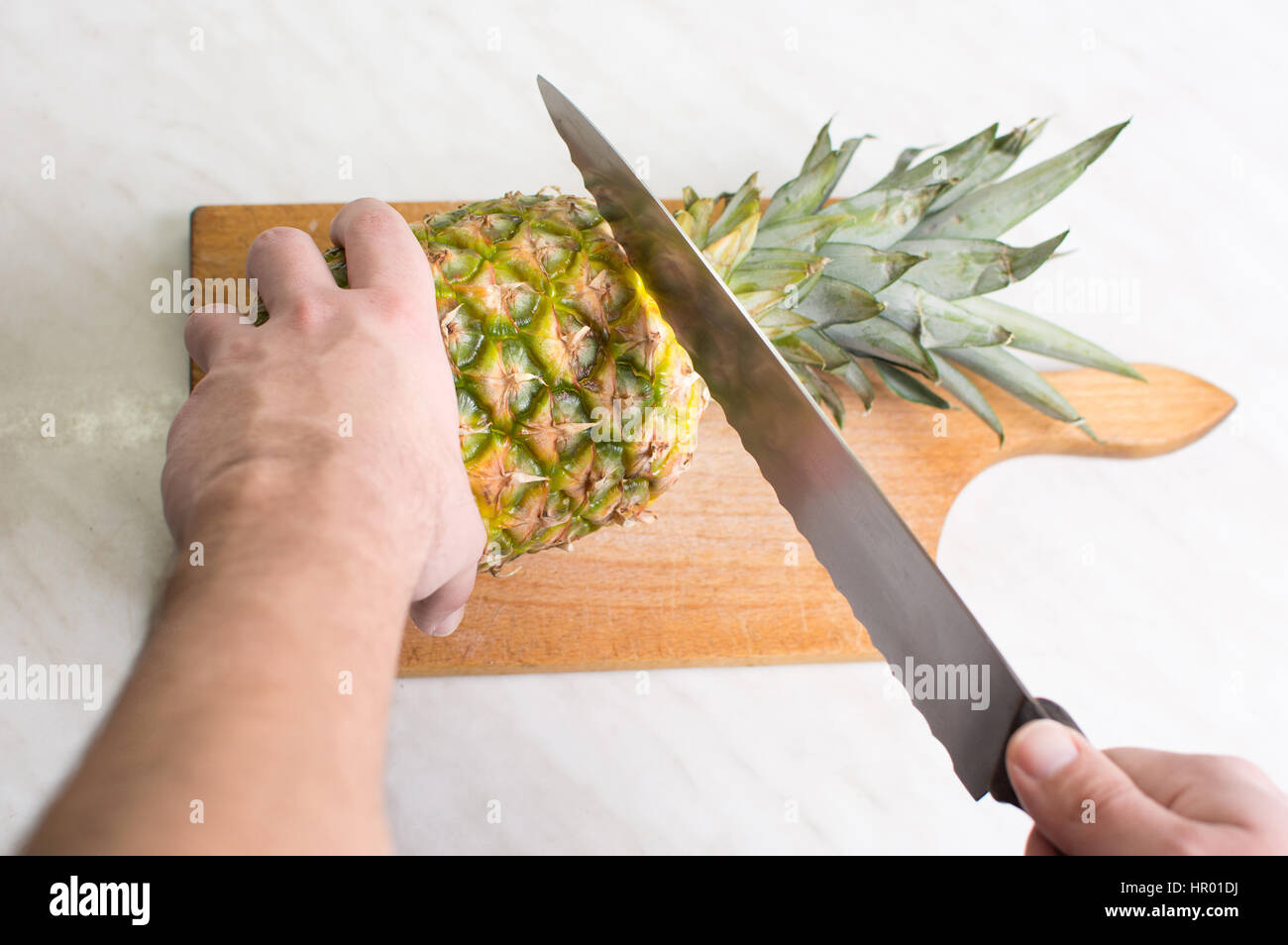 Hände schneiden frischen Ananas auf einem Holzbrett Stockfoto