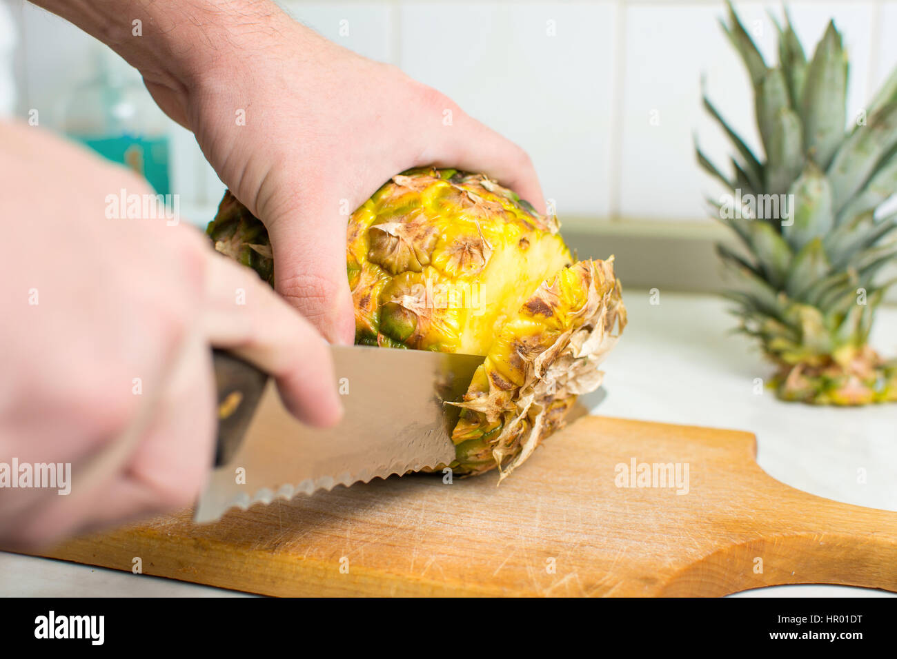 Hände schneiden frischen Ananas auf einem Holzbrett Stockfoto