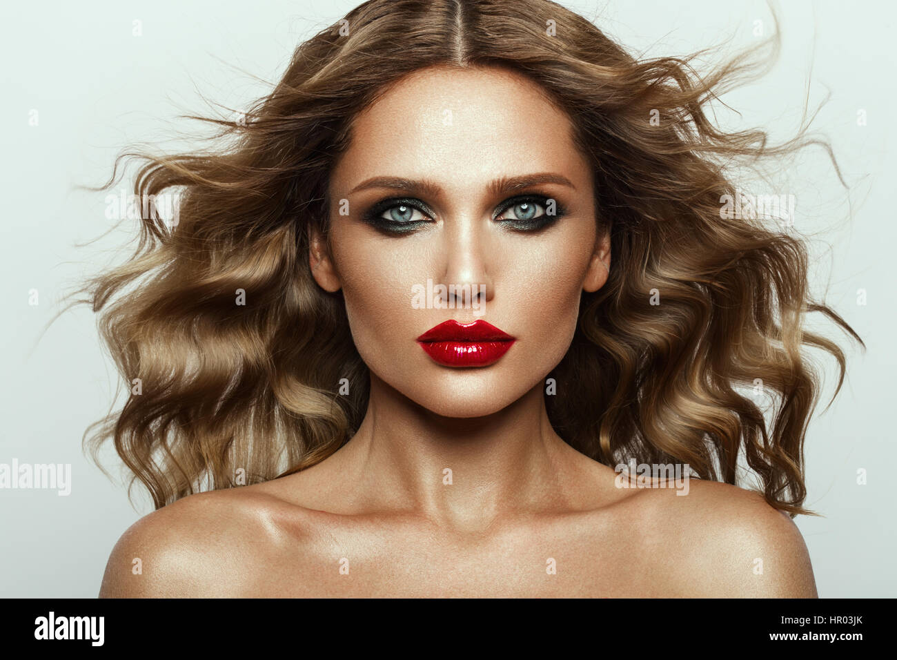 Schönes Gesicht ein Art und Weisemodell mit blauen Augen. Lockiges Haar. Rote Lippen. Studio-Porträt. Stockfoto