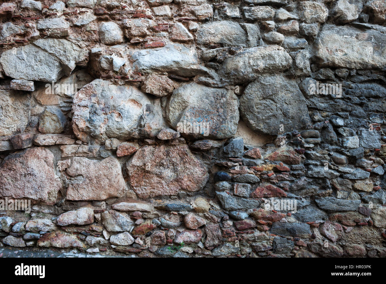 Mittelalterliche Steinmauer Hintergrund oder Textur, die mit großen, mittleren und kleinen Größen der grob geschnittenen Steinen, alten Stadt Girona in Spanien Stockfoto